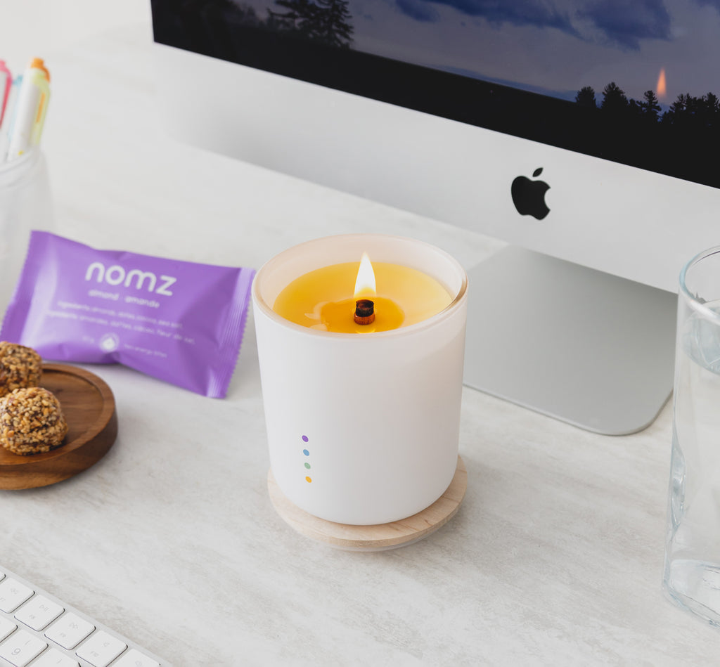 beeswax candle at desk with imac, nomz energy bites, and keyboard in foreground