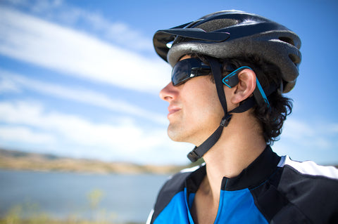 Male cyclist wearing blue bone conduction headphones under bike helmet