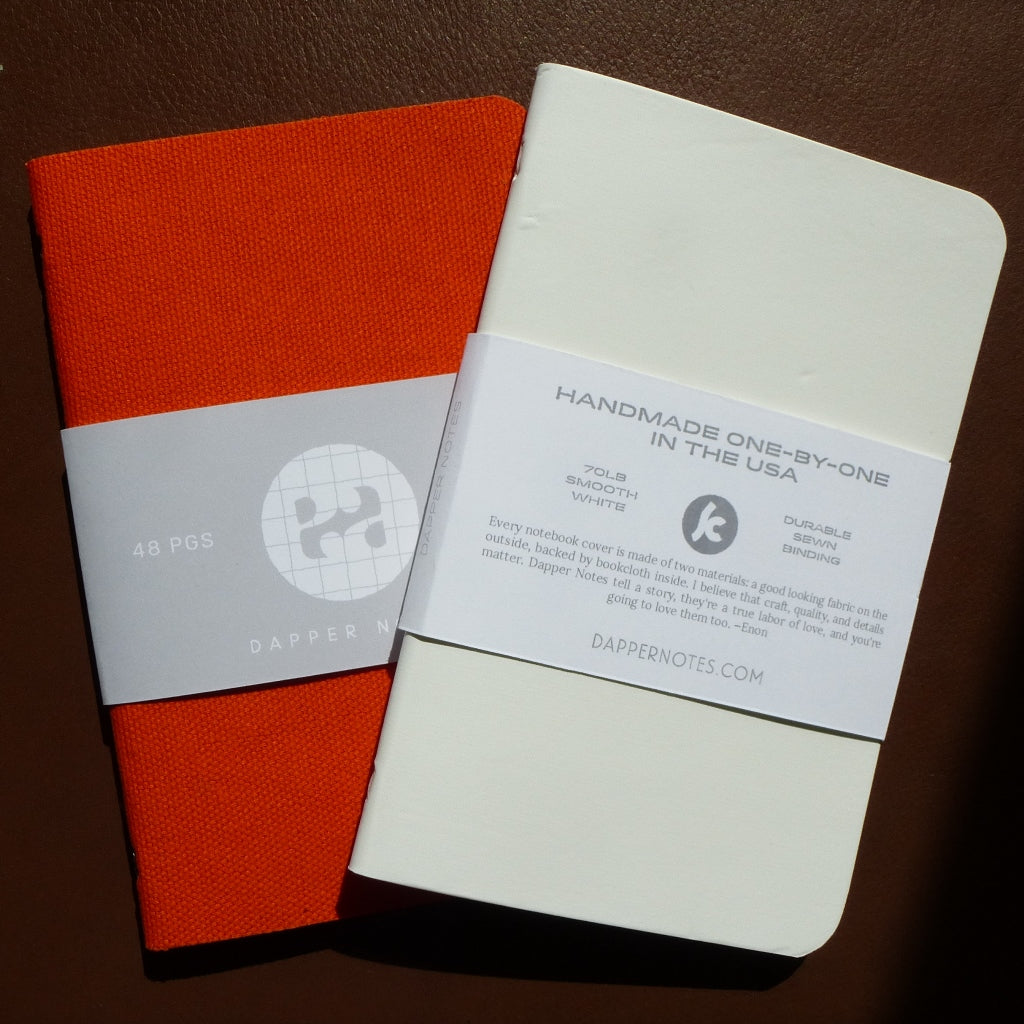 two notebooks, one white, one orange