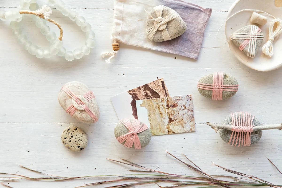 flat layout of decorative items including smooth river rocks wrapped with handwoven decorative pink twine