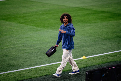 Aziel in blue shirt, white shirt and blue shoes walking on the soccer pitch