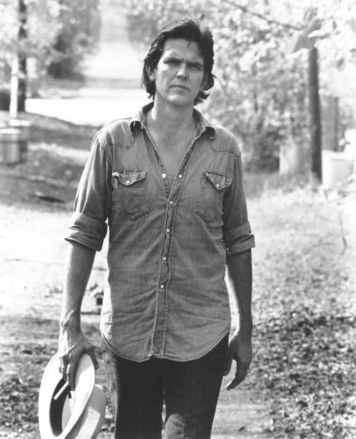 Man in western shirt and holding hat.