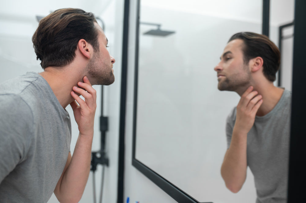 Man examining face for ingrown hairs in mirror