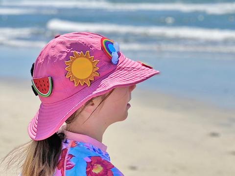 Child wearing hativity hat near the beach in the pink color