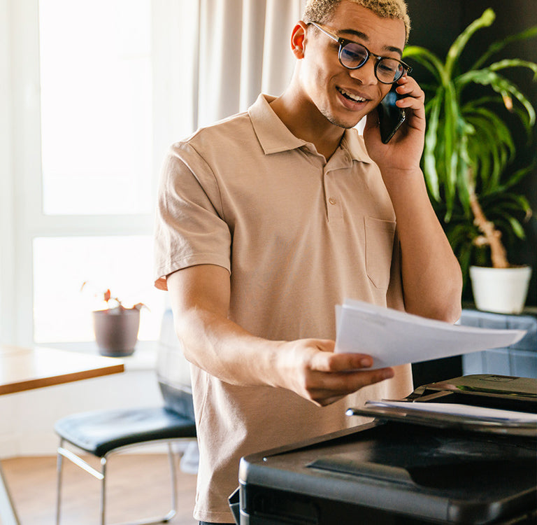 Man holding documents over A4 printer in modern home office