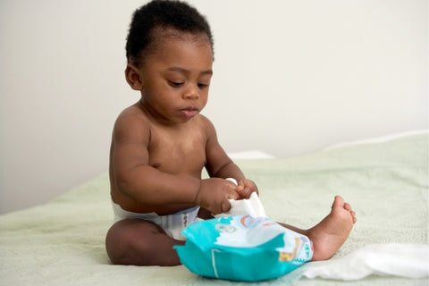 baby playing with a packet of wipes