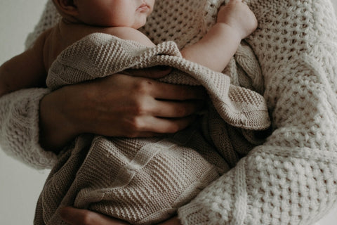 mother holding baby wrapped in blanket