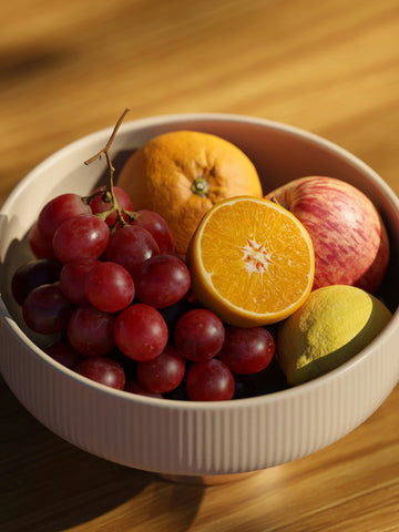 a-white-bowl-filled-with-fruit-on-top-of-a-wooden-table