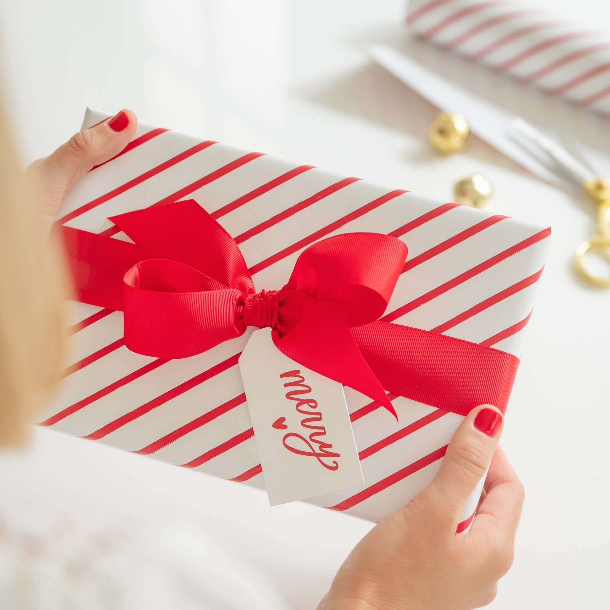 Red stripe gift with red bow and red merry gift tag in hand