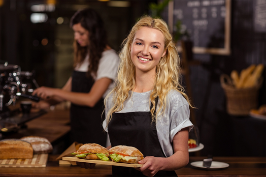 a young waitress holding two burgers in a cafe on a wooden board