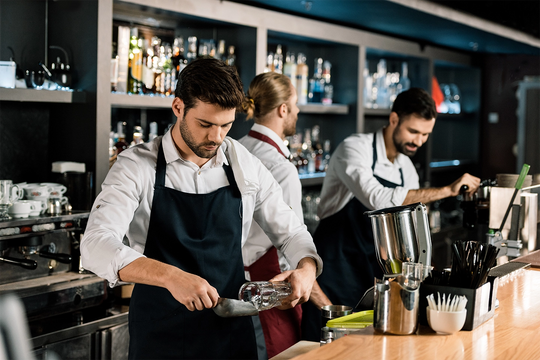 bar staff working behind a bar pulling drinks and pouring ice