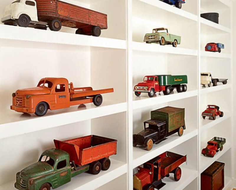 Bookcase displays a variety of large toy trucks.