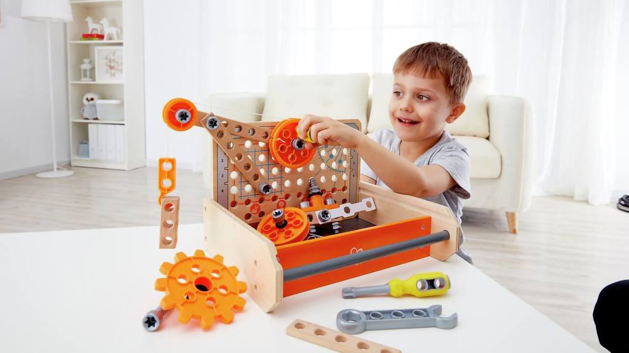 Boy cranking the gear of a Hape Junior Inventory gear set.