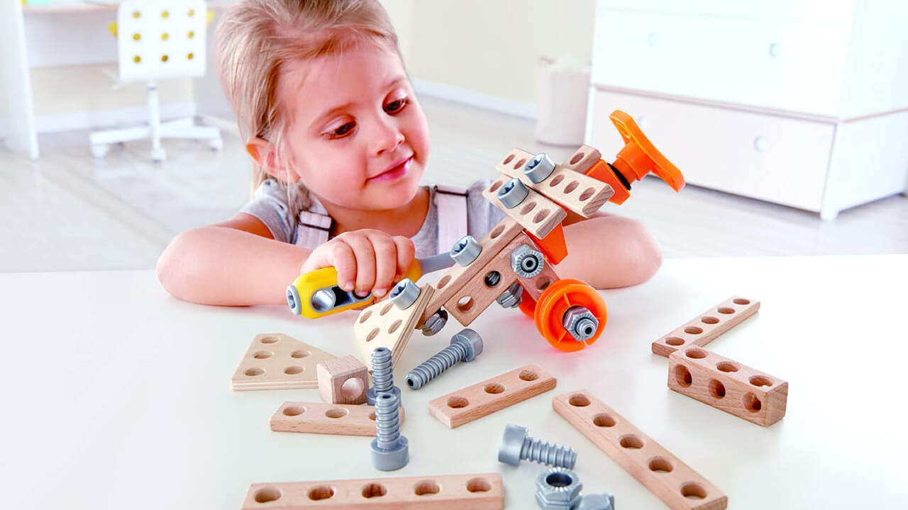 Girl playing with a Hape Junior Inventor construction building set.