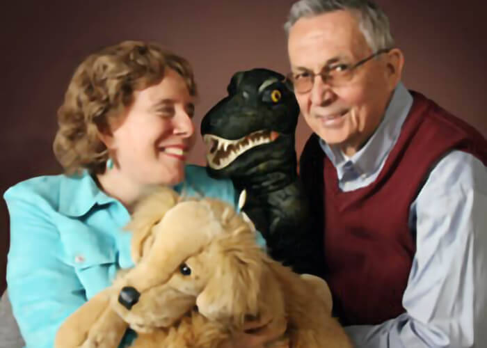 Judy Folkmanis and Atis with dog and dinosaur puppets.