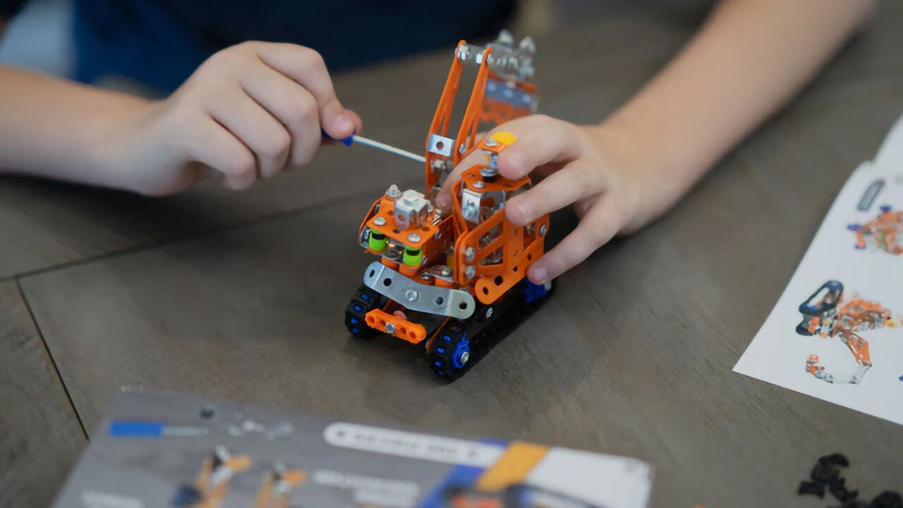 Kid screwing together an Erector set.