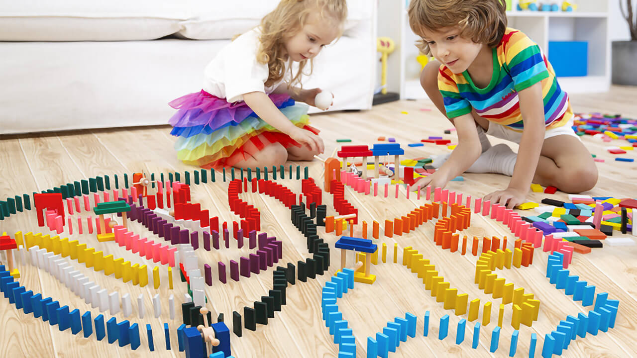 Boy and girl setting up a domino building set.