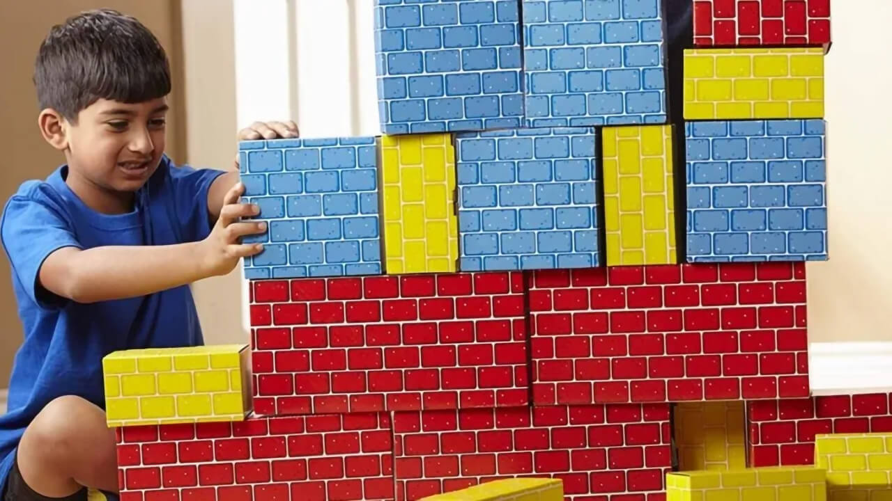 Boy is playing with Melissa and Doug cardboard blocks.