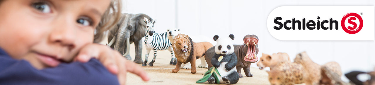 Schleich Brands are represented with this image of a child leaning on a table that has multiple Schleich toys, including an elephant, zebra, lion, panda, hippo, and Schleich logo.