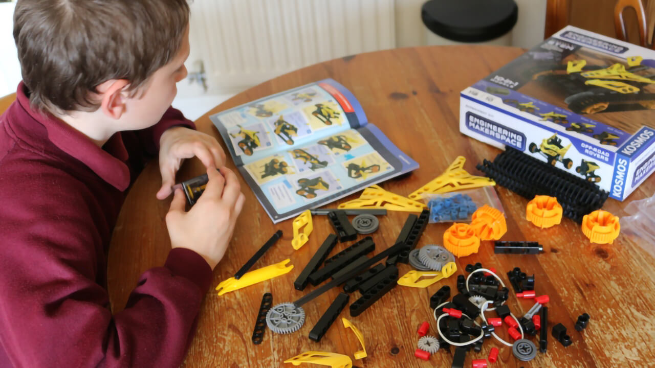 Boy learning about engineering with a Thames and Kosmos building set.