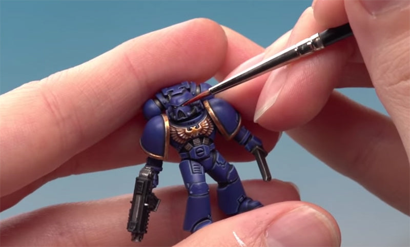 Space Marine being painted with Citadel paint and brush.