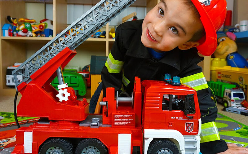 Young boy playing with a firetruck prepares to put it away.