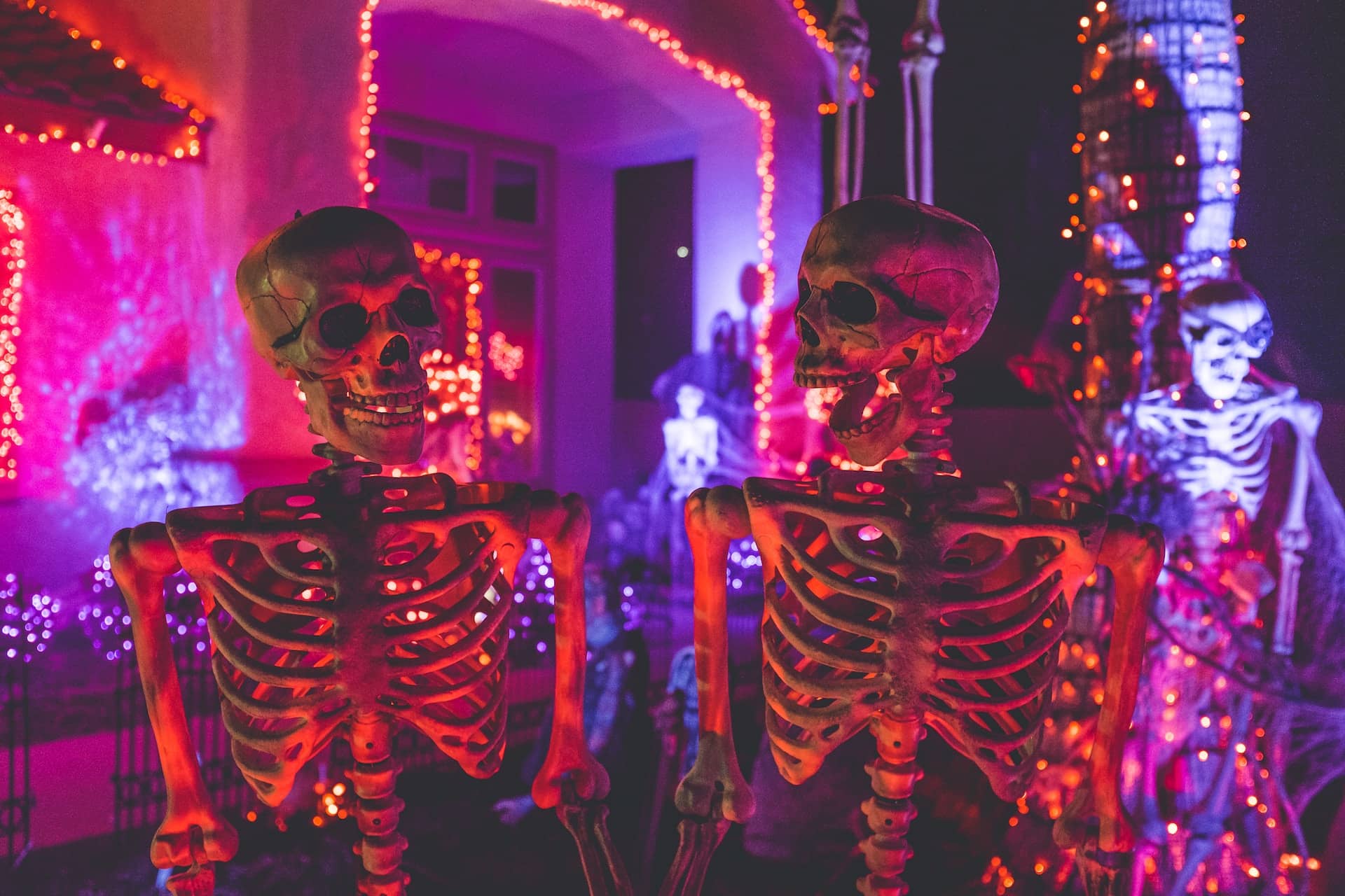 Two skeletons in front of a house decorated for Halloween