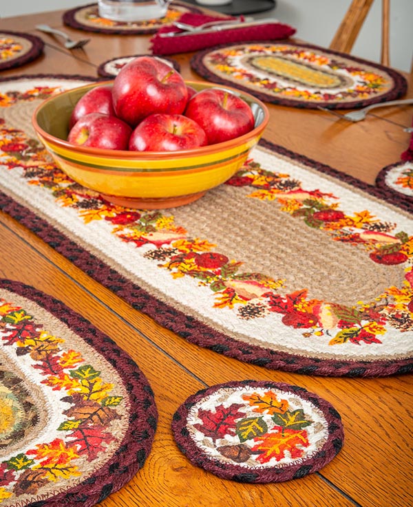 Fall tablescape with autumn leaves designs on placemats, table runner and coaster