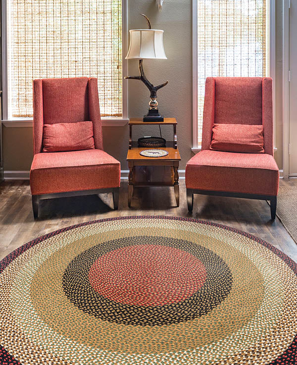 Round braided rug with burgundy, tan and brown braids in rustic home setting.