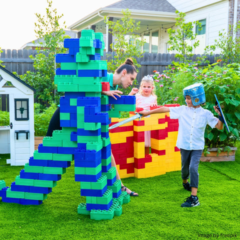 Kids and a parent enjoying an outdoor adventure, using Biggo Blocks to build playful castles and dragons.