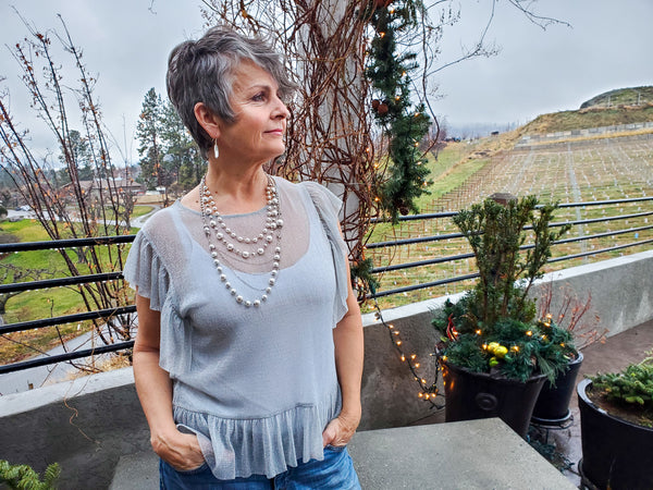 A woman wearing a multi strand pearl necklace and crystal earrings