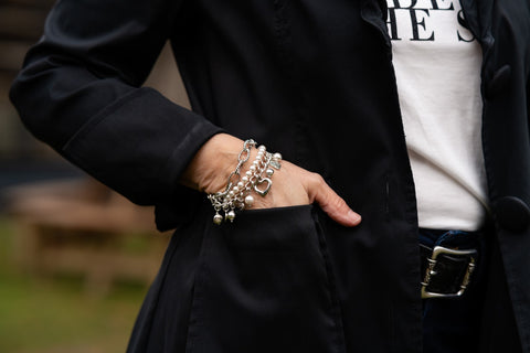 Woman's wrist wearing pearl, pewter and stainless steel charm bracelet