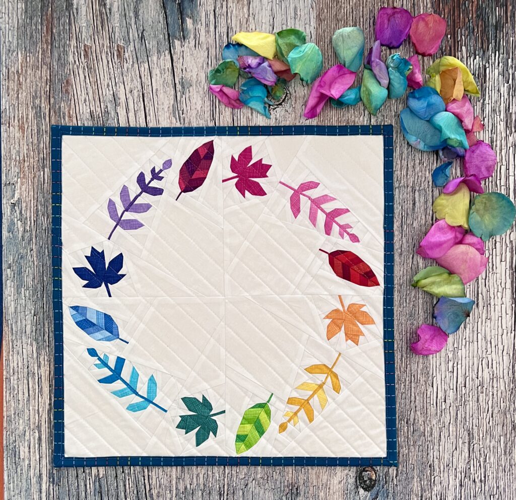 A rainbow wreath of leaves making a bright cheerful mini quilt