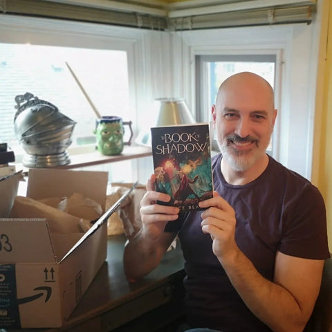 Smiling author Bruce Blake holding copy of The Book of Shadow