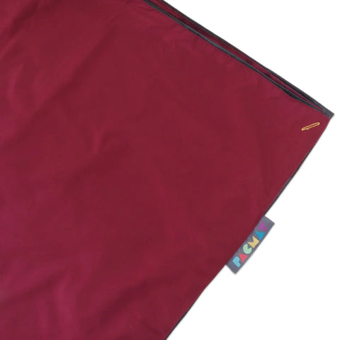 A maroon-colored picnic mat peeks out of the edge of a photo with the PACMAT logo on one side.