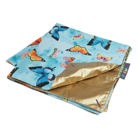A folded up picnic mat, with the main side showing a blue-focused watercolor butterfly pattern. The flip side is shown to be a metallic gold.