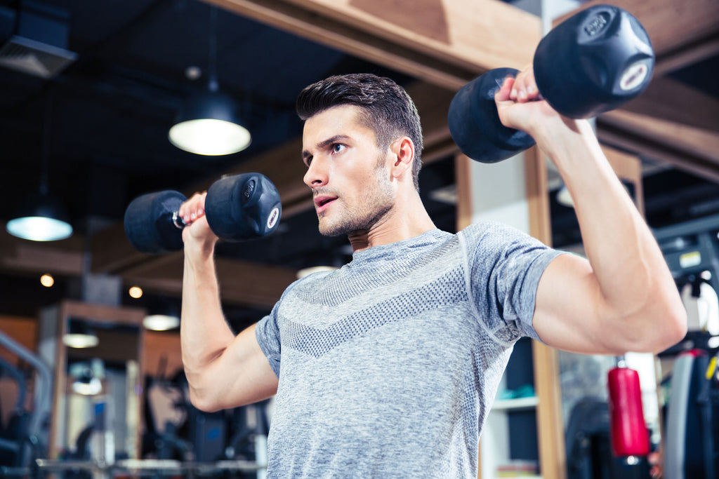 Handsome man lifting weights at the gym while looking straight ahead