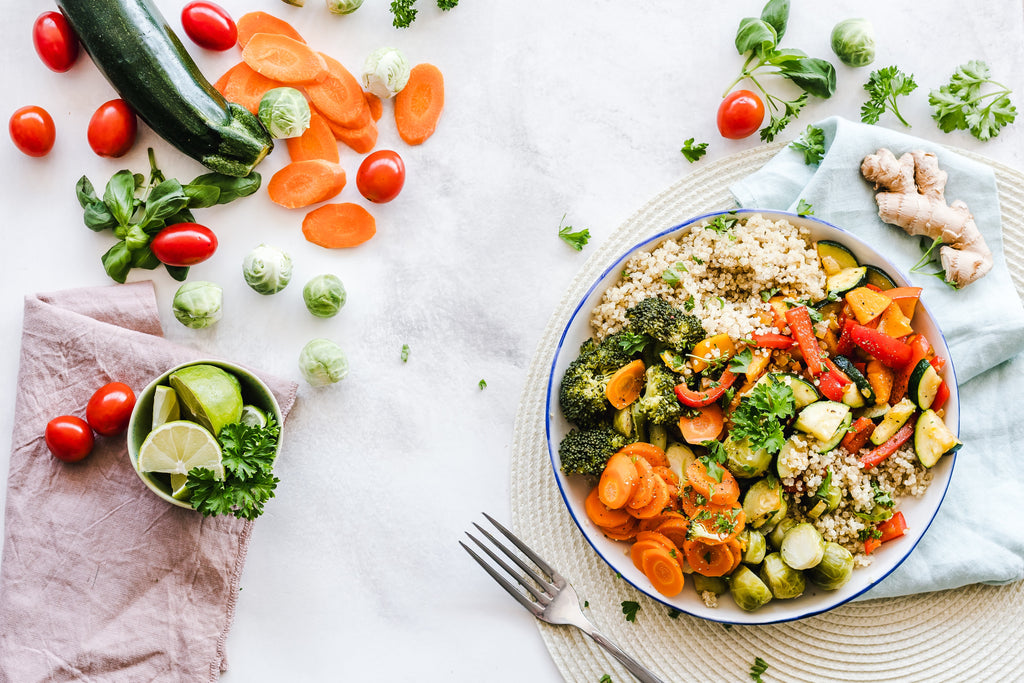  healthy colorful bowl of food surrounded by ingredients and a fork