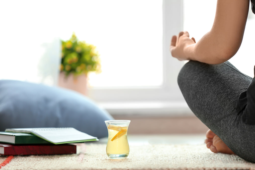 Cup of green tea fat burner with a woman practicing yoga