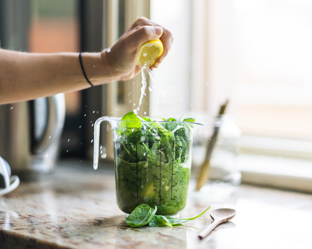 Healthy person squeezing a lemon into green juice to lose weight