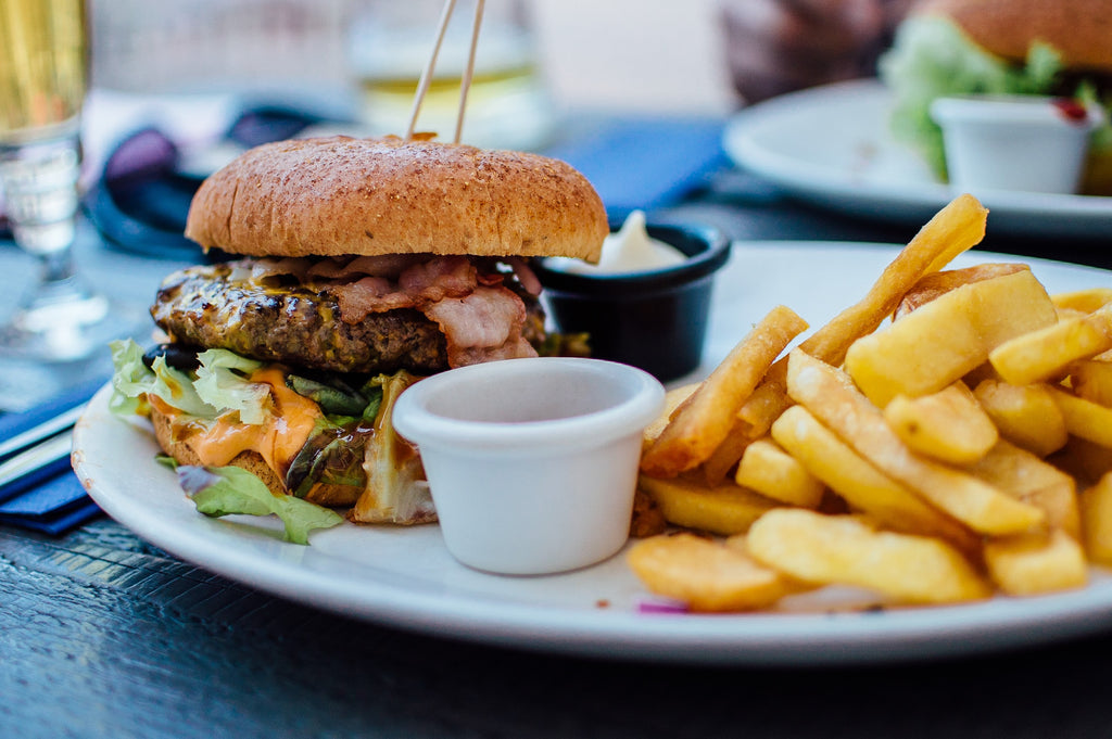 Unhealthy cheeseburger on a plate with a side of french fries