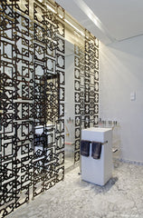 Guest bathroom with a bespoke made metal screen, inspired by a pattern seen in an exhibition on Coptic art, placed in front of the floor to ceiling mirror.
