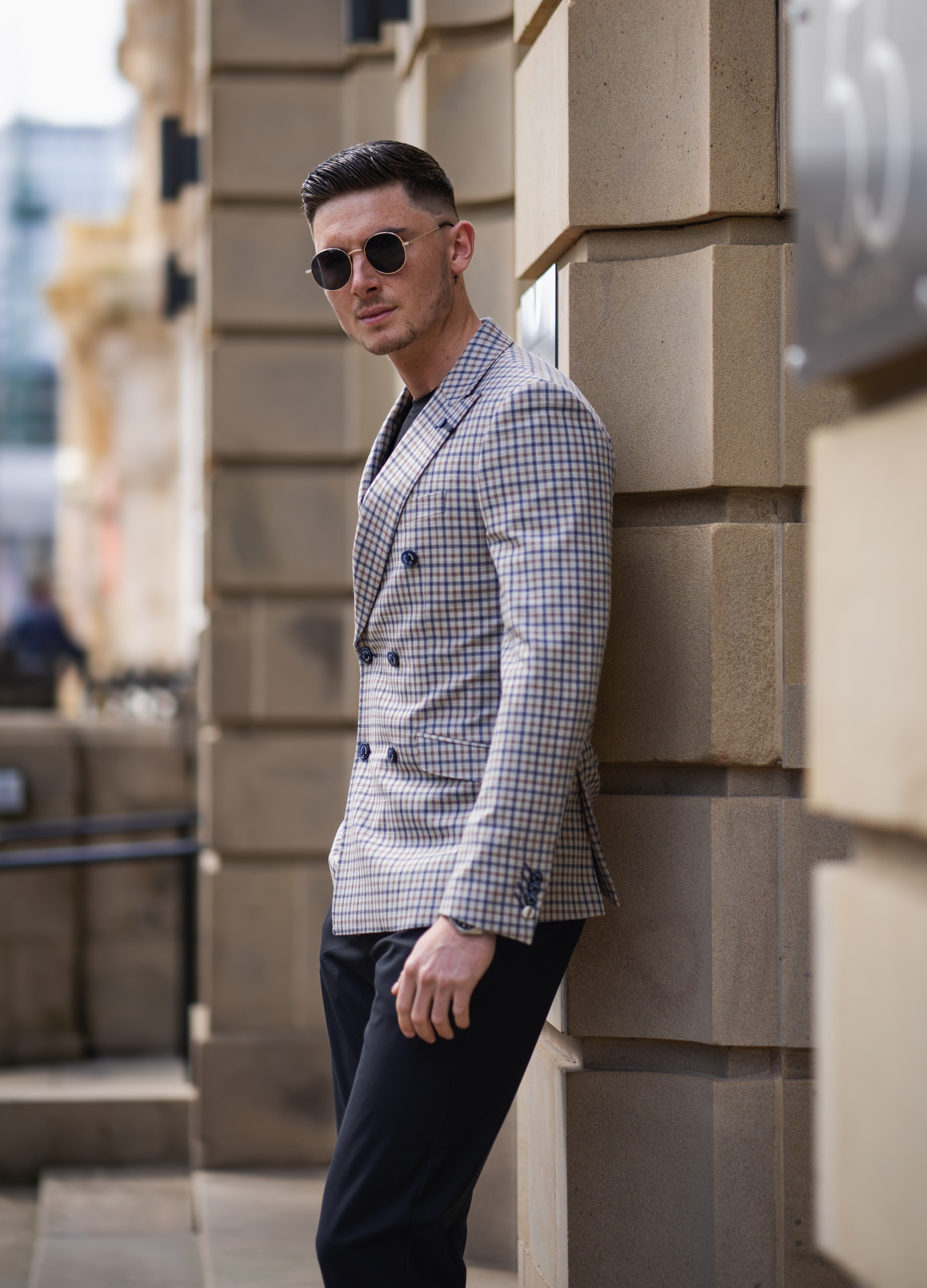 Un homme portant un blazer croisé à carreaux de manière décontractée.