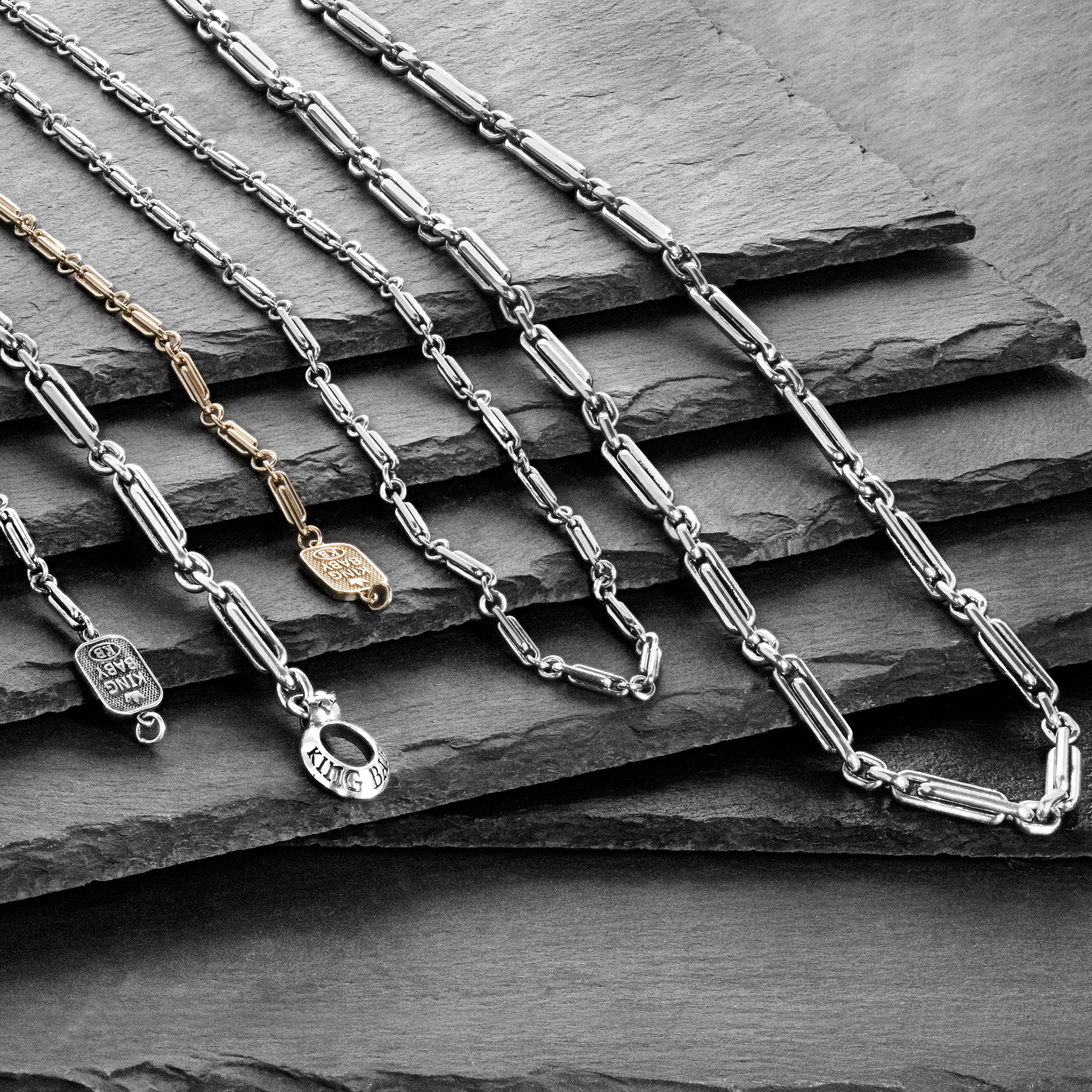 The Paperclip collection necklaces and bracelets cascading down multiple slate slabs.
