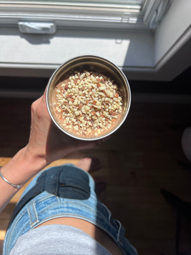 Woman Holding Arbonne FeelFit Protein Shake Topped With Almonds Crumbs On Top