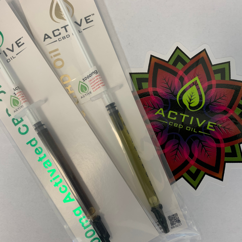 Active CBD Oil 25% Gold and Active CBD Oil 17% Green product syringes next to an Active CBD Oil flower sticker on white background