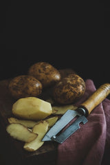 potatoes and peeler on a barrel