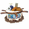 One Piece cake with logo on front, ship wheel design on top edge, character toppers, and brown sugar sand at the base – perfect for anime or pirate-themed celebrations.