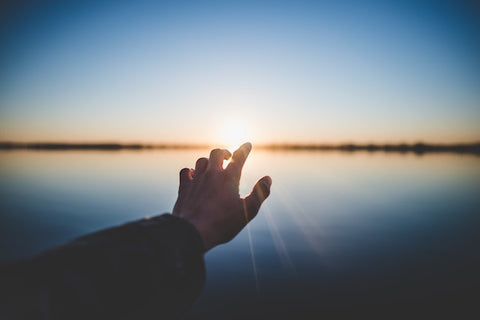 A hand reaching out into the horizon 