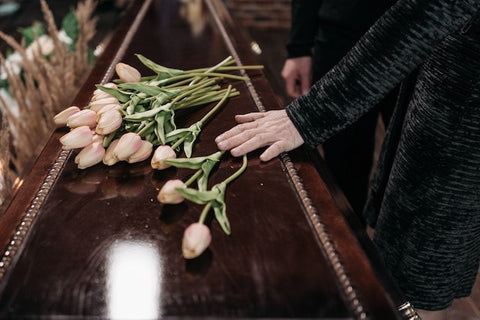 A woman placing flowers on a casket 